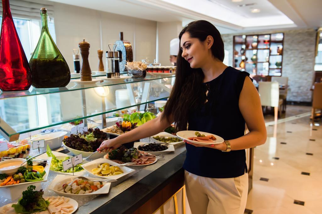 Grand Mercure Majlis Residences Abu Dhabi Eksteriør bilde A woman selecting food from a buffet